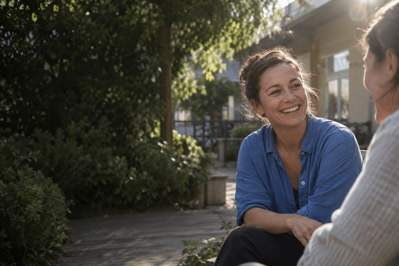 Two colleagues sharing a relaxed conversation in a sunlit courtyard